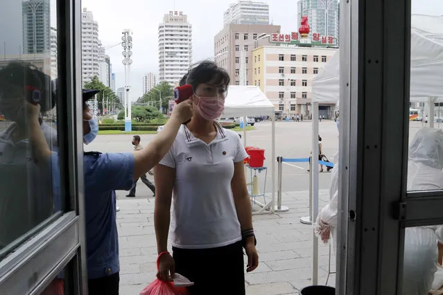 A woman wearing a face mask to help curb the spread of the coronavirus gets fever checked before going into the Pyongyang Railway Station in Pyongyang, North Korea, Thursday, August 13, 2020. (Photo by Jon Chol Jin/AP Photo)