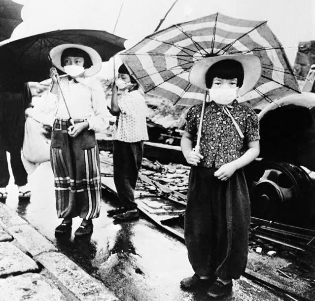 The Japanese of atom-bombed Hiroshima have put the ancient custom of wearing nose and mouth masks while out of doors to a good use. Hiroshima was the first town to be hit by an atom bomb during the war. Japanese girls wearing their masks as they walk through the devestated streets of Hiroshima, Japan, on October 6, 1945. (Photo by AP Photo)