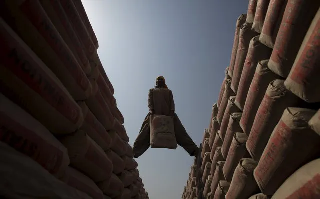A labourer moves sacks of cement from one truck to another bound for Afghanistan at a transit depot in Peshawar, Pakistan September 16, 2015. (Photo by Fayaz Aziz/Reuters)