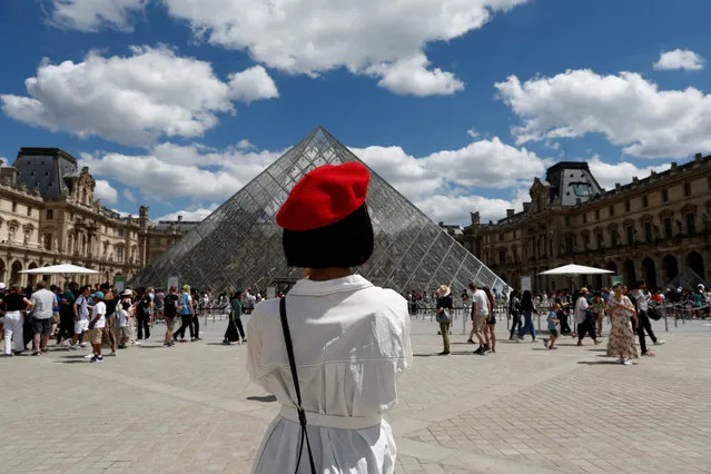 A tourist takes photographs of the Louvre Museum in Paris, France on July 3, 2022. (Photo by Benoit Tessier/Reuters)