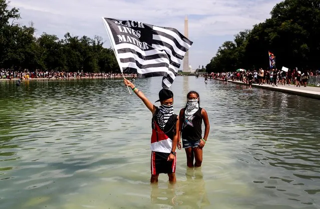 A protester holds a Black Lives Matter flag as he wades into the waters of the Lincoln Memorial reflecting pool as demonstrators gather for the “Get Your Knee Off Our Necks” March on Washington in support of racial justice in Washington, August 28, 2020. Thousands of people gathered to denounce racism and protest police brutality on the anniversary of the march in 1963 where civil rights leader Martin Luther King Jr made his historic “I Have a Dream” speech. (Photo by Tom Brenner/Reuters)