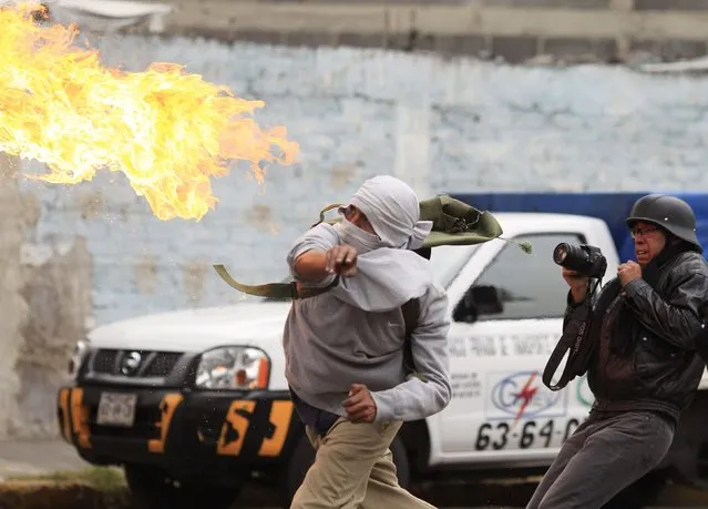 A masked demonstrator throws a petrol bomb towards riot police during a protest over the 43 missing Ayotzinapa students, near the Benito Juarez International airport in Mexico City November 20, 2014. Masked demonstrators threw Molotov cocktails and shot fireworks at police near Mexico City's airport on Thursday as thousands prepared to protest President Enrique Pena Nieto's handling of the apparent massacre of 43 trainee teachers after their abduction on the night of September 26. (Photo by Carlos Jasso/Reuters)