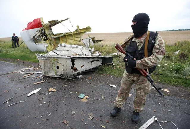A pro-Russian separatist stands at the crash site of Malaysia Airlines flight MH17, near the settlement of Grabovo in the Donetsk region, July 18, 2014. (Photo by Maxim Zmeyev/Reuters)