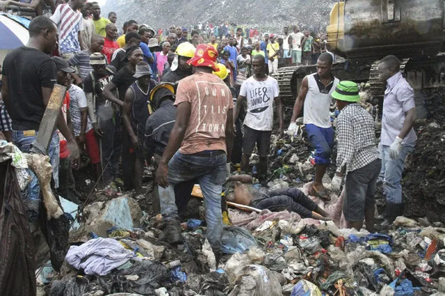 Rescuers recover a body as they search for survivors at the collapse of a garbage mound in Maputo, Mozambique, Monday, February 19, 2018. Mozambican media say at least 17 people died when heavy rains triggered the partial collapse of the mound garbage. (Photo by Ferhat Momade/AP Photo)