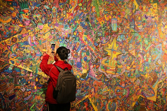 A visitor takes a photo with her mobile phone during the “Out of Orbit” exhibition in Hanoi, Vietnam, 10 July 2025.The first solo exhibition “Out of Orbit” by artist Hoang Anh Trung is held at Mo Art Space and runs from 03 June to 13 July 2025. (Photo by Luong Thai Linh/EPA)