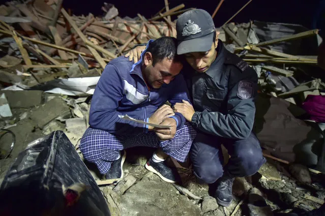An Azerbaijani soldier tries to comfort a man amongst debris as they try to find survivors from destroyed houses in a residential area in Ganja, Azerbaijan's second largest city, near the border with Armenia, after rocket fire overnight by Armenian forces for second time in a week, early Saturday, October 17, 2020. (Photo by Ismail Coskun/IHA via AP Photo)