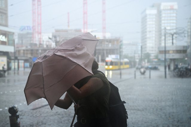 A woman shields herself with an umbrella on a street on Alexanderplatz square during stormy weather in Berlin, Germany on June 26, 2025. (Photo by Annegret Hilse/Reuters)