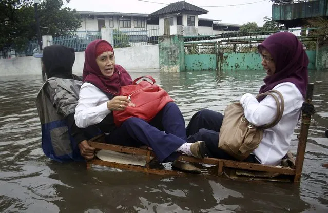 Muslim women sit on a cart as they cross through a flooded street in Bandung, West Java, Indonesia, Wednesday, March 27, 2013. Heavy rain triggered floods in the area Wednesday, submerging hundreds of houses and forcing residents to flee.  (Photo by AP Photo)