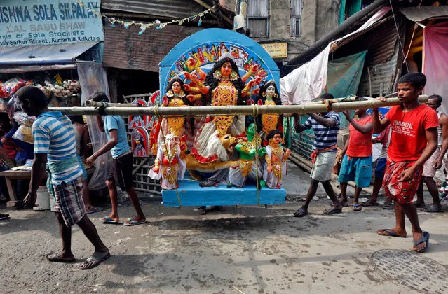 Workers carry an idol of the Hindu goddess Durga through a street towards a pandal, or a temporary platform, ahead of the Durga Puja festival in Kolkata, India, October 5, 2016. (Photo by Rupak De Chowdhuri/Reuters)