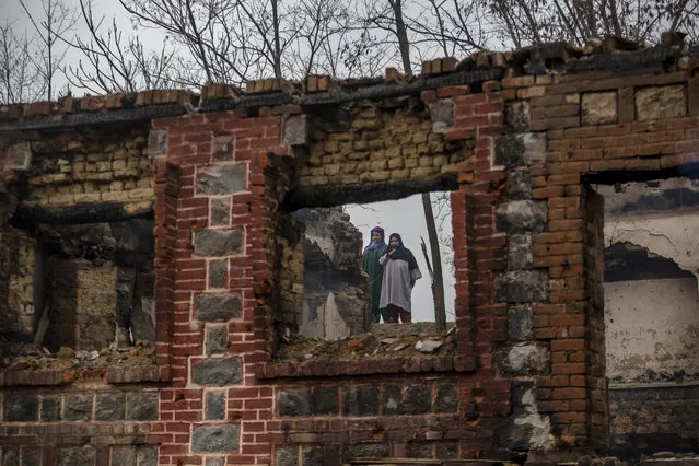 Kashmiri women stand near houses destroyed in a gunbattle on the outskirts of Srinagar, Indian controlled Kashmir, Friday, March 16, 2018. Officials say two militants have been killed and a soldier wounded in a gunbattle with Indian government forces in disputed Kashmir. (Photo by Dar Yasin/AP Photo)