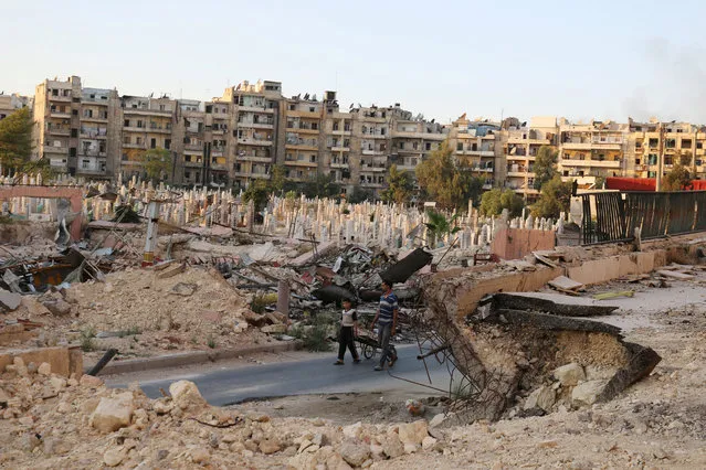 People walk near an over-crowded graveyard in the rebel held al-Shaar neighbourhood of Aleppo, Syria October 6, 2016. (Photo by Abdalrhman Ismail/Reuters)