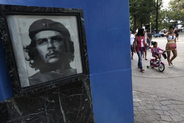 People walk near a photograph of late revolutionary hero Ernesto “Che” Guevara in Havana December 17, 2014. (Photo by Enrique De La Osa/Reuters)