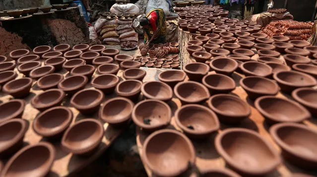 An Indian woman arranges an earthen lamp for the upcoming Diwali festival in Mumbai, India, Friday, October 30, 2015. Diya is a small earthen lamp primarily used during Diwali, the festival of lights. Also, known as 'deep', diya is traditionally made of clay. During Diwali, the earthen lamps are used for illuminating and decorate the entire home and premises, apart from aarti. The diya is filled with ghee or oil, which work as fuel for it. (Photo by Divyakant Solanki/EPA)