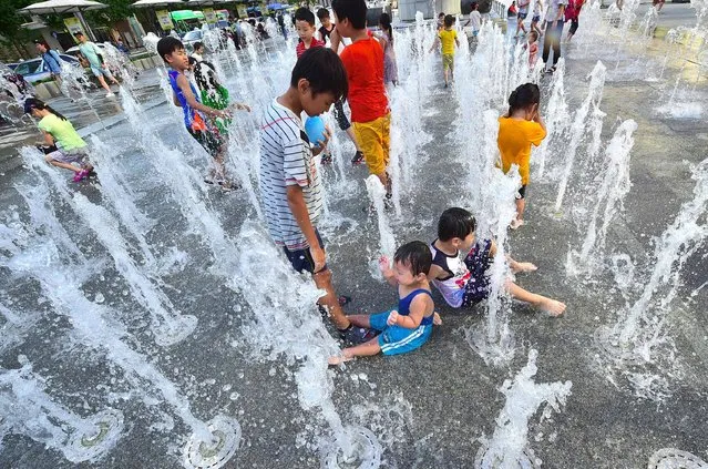 Children play in a fountain to beat the heat in central Seoul on August 4, 2016. South Korea's state weather agency issued a heat wave warning for Seoul for the first time this year, as the daytime high is expected to stay above 35C (95F) for two or more consecutive days, according to state media. (Photo by Jung Yeon-Je/AFP Photo)