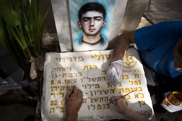 Family members of Israeli soldier Soli Mizrahi repaint his gravestone at Kiryat Shaul military cemetery on the eve of memorial Day in Tel Aviv, Israel, Tuesday, April 17, 2018. Israel marks the annual Memorial Day in remembrance of soldiers who died in the nation's conflicts, beginning at dusk Tuesday until Wednesday evening. (Photo by Oded Balilty/AP Photo)