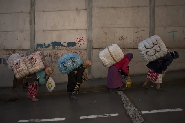Women porters carry bundles on their backs for transport across the El Tarajal boarder separating Morocco and Spain's North African enclave of Ceuta, in Ceuta on December 4, 2014. (Photo by Jorge Guerrero/AFP Photo)