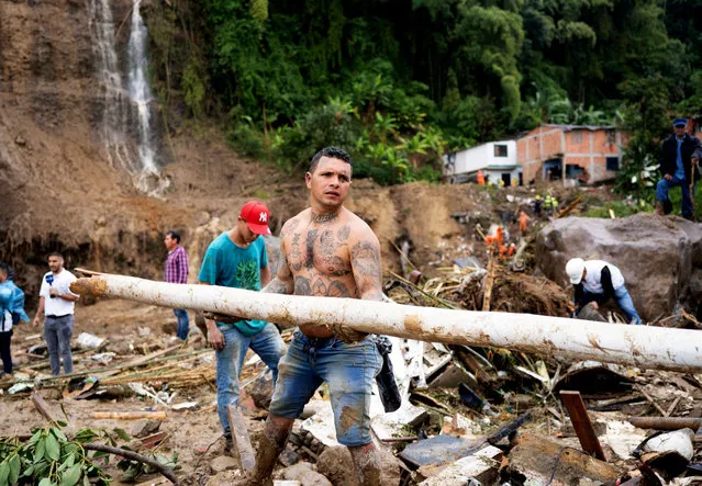 People remove debris following a landslide caused by heavy rains, that killed and injured residents and destroyed homes, in Pereira, Colombia, February 8, 2022. (Photo by Vladimir Encina Duque/Reuters)