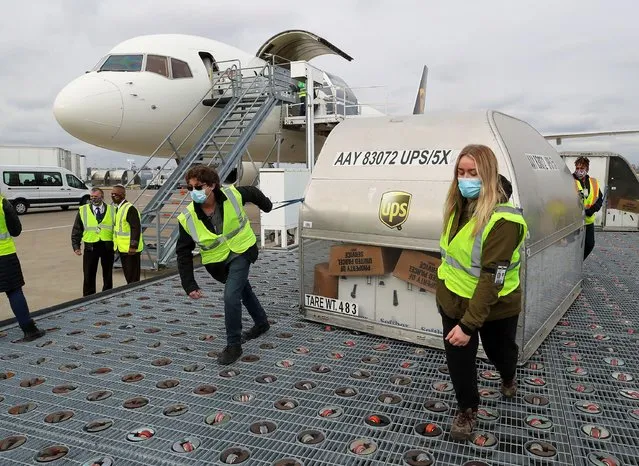 UPS employees move one of two shipping containers of the Pfizer COVID-19 vaccine on ramp at Louisville Muhammad Ali International Airport in Louisville, Kentucky, December 13, 2020. (Photo by Michael Clevenger/Pool via Reuters)
