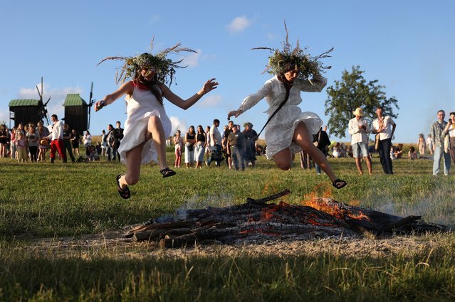 Participants jump over a bonfire as they celebrate the Pagan holiday of Ivan Kupala, a traditional holiday that has been observed in Ukraine since pre-Christian times, in Kyiv, on June 23, 2024, amid the Russian invasion in Ukraine. (Photo by Anatolii Stepanov/AFP Photo)
