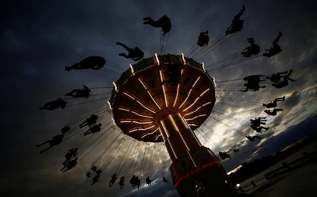 People ride on a merry-go-round carousel during sunset in Stockholm, Sweden, August 16, 2016. (Photo by Hannibal Hanschke/Reuters)