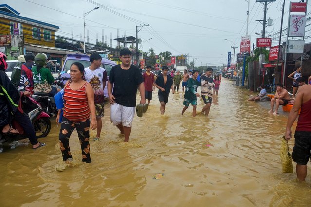 Residents wade through a flooded street in Liloan town, Cebu province, on November 4, 2025, after Typhoon Kalmaegi hit overnight. Residents sought refuge on rooftops and cars floated through flooded streets on November 4 as Typhoon Kalmaegi battered the central Philippines, leaving at least two people dead. (Photo by Alan Tangcawan/AFP Photo)