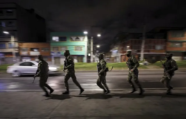 Soldiers run to a military truck to change checkpoint during an official continuous multi-day curfew in an effort to contain the spread of new coronavirus infections, in Bogota, Colombia, Friday, January 22, 2021. Colombia's capital city is reimposing lockdown measures as COVID-19 infections rise around the country. (Photo by Fernando Vergara/AP Photo)