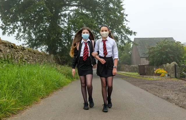 Twins Louisa and Imogen, who turned 12 years old two days ago, set off from their home on a murky morning for their first day of secondary school at North Berwick High as S1 pupils in Camptoun, Scotland on August 13, 2020. They missed out on the normal Induction Days in P7 due to the Covid-19 pandemic lockdown. (Photo by Sally Anderson News/Alamy Stock Photo)