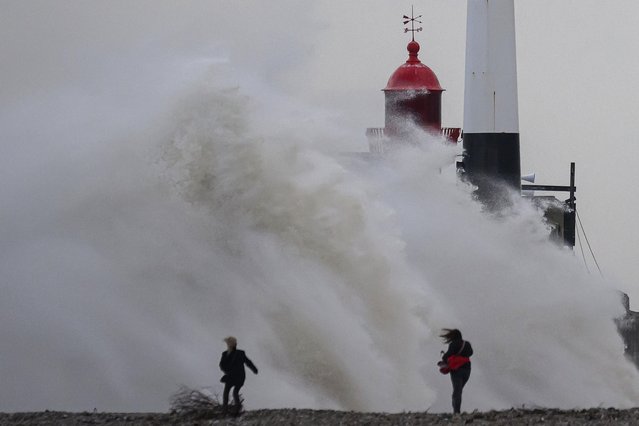 Pedestrians walk as waves break on the Digue Nord lighthouse in Le Havre, western France, on October 23, 2025. (Photo by LLoic Venance/AFP Photo)