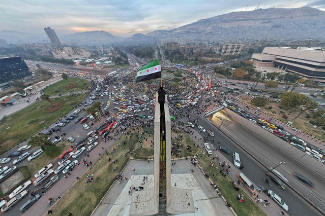 An aerial view shows a Syrian man waving the independence-era flag Syrian flag at Damascus' central Umayyad Square on December 11, 2024. (Photo by Bakr Alkasem/AFP Photo)