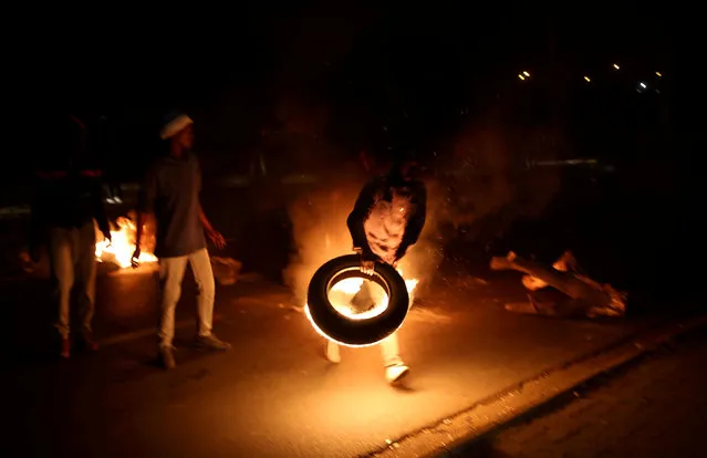 A man blocks a road with a burning tyre while protesting against electricity cuts in Klipspruit Soweto, Johannesburg, South Africa, July 4,2018. (Photo by Siphiwe Sibeko/Reuters)