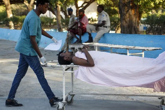 A medical worker pushes the stretcher of a civilian man wounded in an attack on the Afrik hotel in the capital Mogadishu, Somalia Sunday, January 31, 2021. (Photo by Farah Abdi Warsameh/AP Photo)