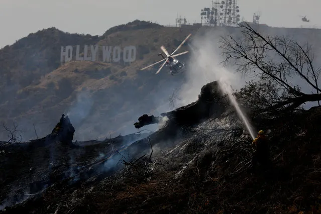 Firefighters work on a fire near the landmark Griffith Observatory in the hills overlooking the Hollywood sign in Los Angeles, California, U.S. July 10, 2018. (Photo by Patrick T. Fallon/Reuters)