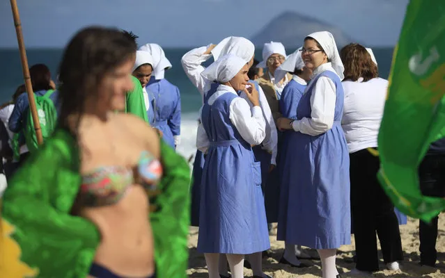 Nuns and sunbathers wait for the arrival of Pope Francis on Copacabana beach in Rio de Janeiro, July 26, 2013. Pope Francis on Thursday issued the first social manifesto of his young pontificate, telling slum dwellers in Brazil that the world's rich must do much more to wipe out vast inequalities between the haves and the have-nots. (Photo by Ricardo Moraes/Reuters)
