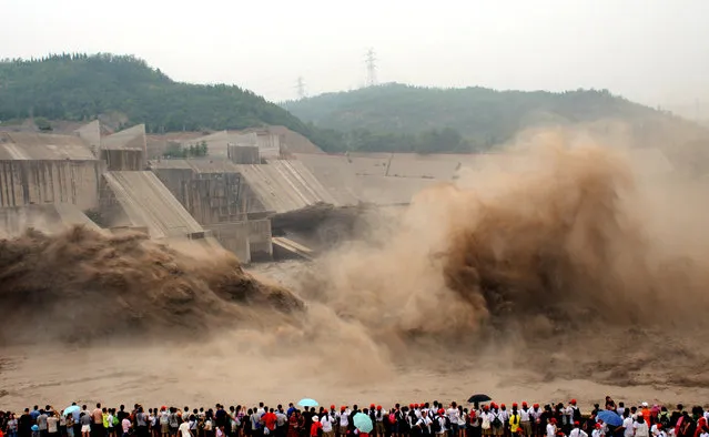 People watch as water and sand is blasted from the Xiaolangdi Dam on the Yellow River on July 8, 2018 in Jiyuan, Henan Province of China. The number of tourists at Xiaolangdi Dam has reached 20,000 on July 8, since the sand washing in the Yellow River started on July 3 in Jiyuan. (Photo by VCG/Getty Images)