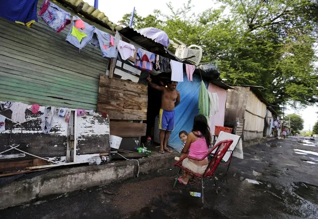 A woman sits next to a makeshift shelter with her son in Asuncion, December 27, 2015. (Photo by Jorge Adorno/Reuters)