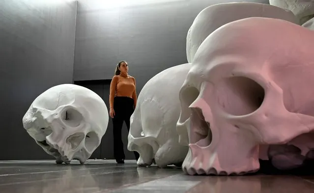 A person looks at Australian artist Ron Muecks large-scale installation “Mass” which comprises more than 100 hand-cast skulls that collectively weigh approximately 5000 kilograms at an exhibition at the National Gallery of Victoria (NGV) in Melbourne on May 18, 2022. (Photo by William West/AFP Photo)