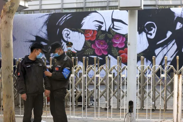Chinese security personnel stand on duty near an art work outside the United States Embassy in Beijing on April 6, 2021. China accused the U.S. of causing humanitarian disasters through foreign military interventions in a report Friday, April 9, 2021 that was the latest broadside by Beijing amid increasingly contentious relations with the Biden administration. (Photo by Ng Han Guan/AP Photo)