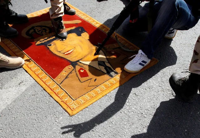 Anti-Gaddafi fighters step on a carpet bearing a picture of Muammar Gaddafi in the north of the besieged city of Bani Walid, Libya  September 16, 2011. The forces of Libya's new leaders attacked two besieged towns, storming into Bani Walid and pushing forward at Sirte, as they tried to finish off resistance from diehard supporters of Muammar Gaddafi. (Photo by Zohra Bensemra/Reuters)