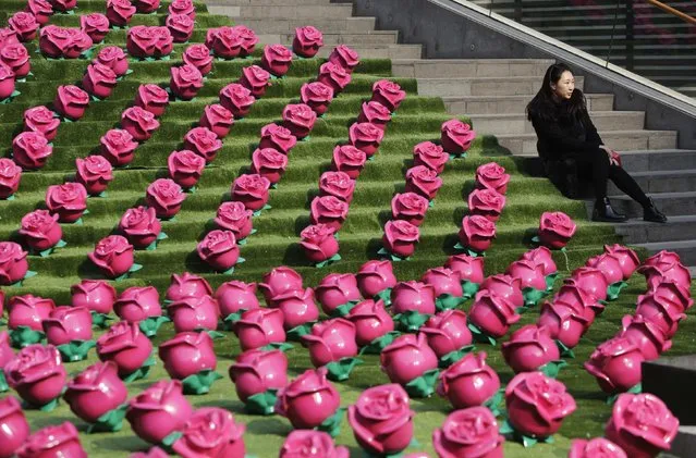 A woman poses for photographs next to an installation art work of roses at a shopping center on Valentine's Day, in Beijing February 14, 2015. (Photo by Jason Lee/Reuters)