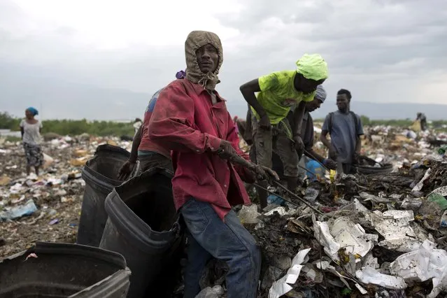In this August 23, 2018 photo, Changlair Aristide pauses as he picks through the trash with a metal rod, alongside others looking for valuable items to use or sell, at the Truitier landfill in the Cite Soleil slum of Port-au-Prince, Haiti. “I'm looking for all kind of items to sell to take care of my family because I don't want my children to follow me into this crappy job”, he said. (Photo by Dieu Nalio Chery/AP Photo)