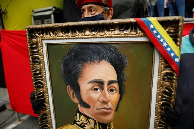 A supporter of Venezuela's President Nicolas Maduro holds a painting with the image of Simon Bolivar while participating in a march to commemorate May Day in Caracas, Venezuela, May 1, 2021. (Photo by Leonardo Fernandez Viloria/Reuters)