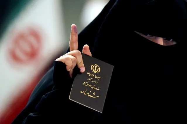 An Iranian woman holds her passport as she shows her ink-stained finger after casting her vote during Iranian presidential election at the Iranian consulate, in Najaf, Iraq, June 18, 2021. (Photo by Alaa Al-Marjani/Reuters)