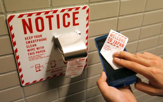 A man demonstrates a toilet roll for wiping smartphones, installed by Japanese mobile phone company NTT Docomo, in a high-tech bathroom equipped with bidet and heated seat at Narita international airport in Narita, Japan, December 28, 2016. (Photo by Toru Hanai/Reuters)