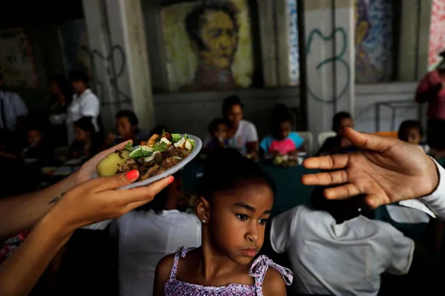 A child looks on, as volunteers of Venezuelan presidential candidate Javier Bertucci of the Esperanza por el Cambio party give food plates to women and children as part of a Mother's Day celebration, during a campaign rally in Caracas, Venezuela, May 13, 2018. (Photo by Carlos Jasso/Reuters)