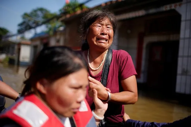 Villager Mai Yu, 56, cries as she asks rescue workers to help her family while standing in floodwaters following heavy rainfall at a village in Xinxiang, Henan province, China on July 24, 2021. (Photo by Aly Song/Reuters)