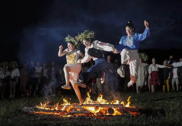 Ukrainians jump over a bonfire as they celebrate the traditional pagan holiday of Ivana Kupala in Kiev, Ukraine, 06 July 2021. Ivana Kupala is celebrated on the shortest night of the year, marking the beginning of summer, and is observed in Ukraine, Belarus, Poland, and Russia. (Photo by Sergey Dolzhenko/EPA/EFE)