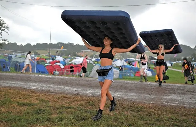 Festivalgoers carry inflatable mattresses in the rain on the first day of the Glastonbury festival in the village of Pilton, in Somerset, southwest England, on June 21, 2023. The festival takes place from June 21 to June 26. (Photo by Oli Scarff/AFP Photo)