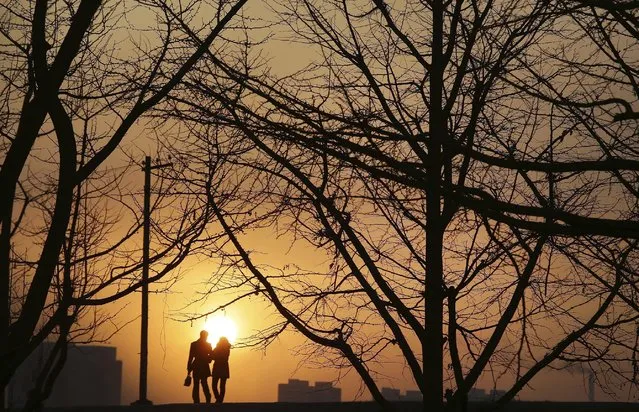 In this Friday, January 6, 2017 photo, a couple is silhouetted against the setting sun as they walk along the Taedong River bank in Pyongyang, North Korea. (Photo by Wong Maye-E/AP Photo)