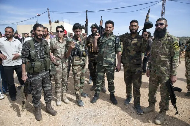 Syrian solders pose for a picture in Maarzaf, about 15 kilometers west of Hama, Syria, Wednesday, March 2, 2016. Local leaders and elders signed a declaration pledging to abide by a truce in Maarzaf. The Russian military has helped mediate signing the document. (Photo by Pavel Golovkin/AP Photo)