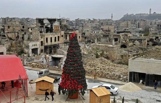 Workers set up a Christmas tree at al-Hatab square, one of the oldest in Syria's northern city of Aleppo, on December 12, 2022. (Photo by AFP Photo/Stringer)